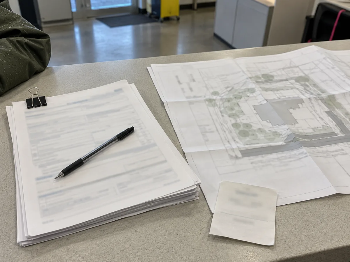 Clipped permit paperwork and a pen on a public counter, the filing for a flood repair in Federal Way, WA